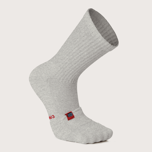 Front view of a single light gray Crease Beast Pocket Crew Sock with a red and blue tag on the ankle.